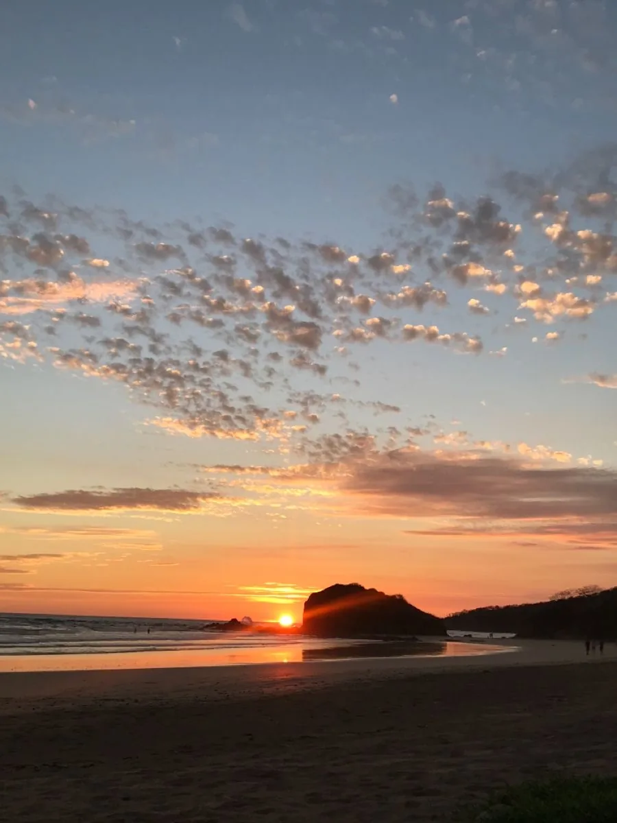 Last light over the headland, low tide, the sand still holding the reflection. Sunsets are the dry season's consolation prize for the smaller swell.